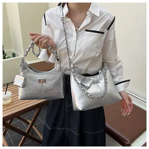 Detail van zilveren geplooide metallic tas met kettingband en metalen draaisluiting
