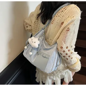 Detail of light blue crescent tote bag with utility pocket and white cloud charm
