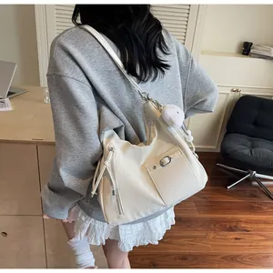 Detail of white PU leather hobo bag with tassel drawstring and plush doll charm
