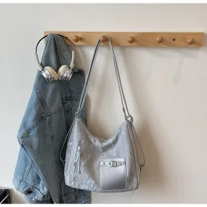 Detail of silver textured tote bag with metal buckle and vertical zipper tassel