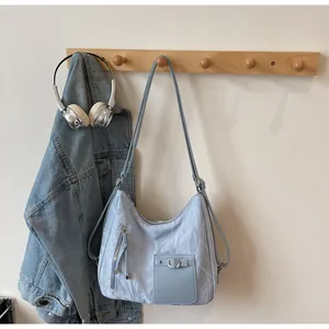 Detail of light blue-grey textured nylon shoulder bag with buckle and zipper pockets