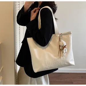 Detailed view of a white PU leather tote bag with pebble texture and bear charm