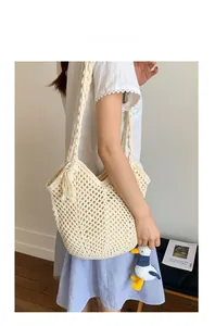 Detail of cream woven shoulder bag with hollow mesh pattern and cute duck charm