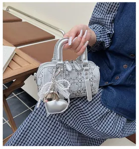 Detail view of silver Boston bag with metal studs and decorative heart charm