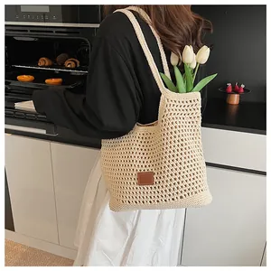 Dettaglio borsa shopper beige all'uncinetto con design a rete e etichetta in pelle