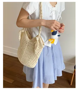 Detail of cream woven tote bag with fringe tassels, braided strap and cute duck charm