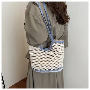 Dettaglio borsa tote intrecciata a mano con maglia beige e spalline blu a contrasto