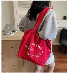 Detail of red canvas tote bag with drawstring closure and white circular lettering