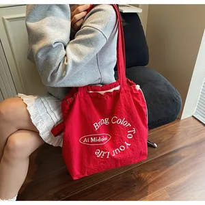 Detail of red drawstring canvas bag with artistic Bring Color To Your Life white lettering