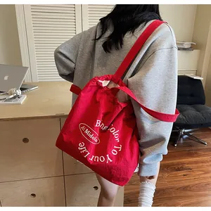 Detail of red canvas bucket bag with drawstring closure and white printed logo