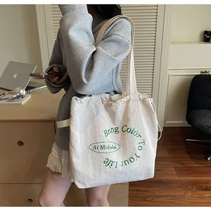 Detail of white canvas tote bag with green Bring Color To Your Life text print
