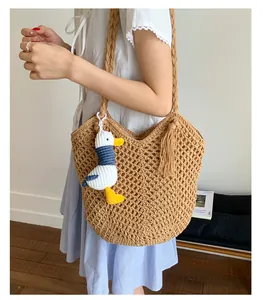 Close-up of woven straw tote bag featuring detailed hollow crochet and stylish side fringes