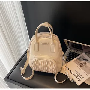 Detail of beige quilted leather mini backpack with mesh paneling on office desk
