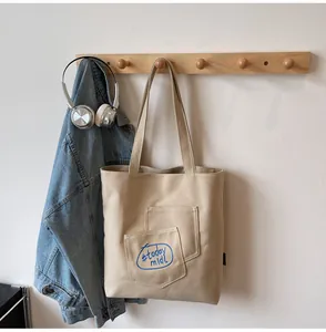 Close-up of beige canvas tote bag with blue embroidered today midi lettering