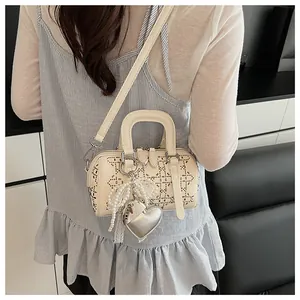 Detail of cream denim Boston bag with lace hollow pattern, pearls and heart charm