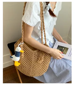 Detail of hollow woven cotton straw bag with braided strap and cute duck charm accessory