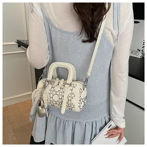Chic off-white Boston bag with silver studs and heart pearl charm in a street style look