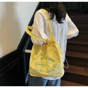 Detail of yellow drawstring tote bag with green typography and crinkled texture