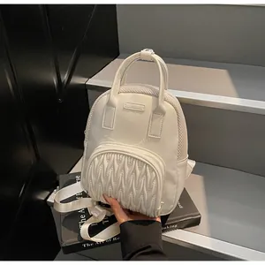 Detail of white leather mini backpack showing wavy quilted pocket and mesh side panels