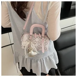 Detail of white denim Boston bag featuring metal studs, pearl bow and heart charm