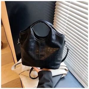 Dettaglio borsa a mano nera con motivo a coccodrillo e finitura lucida elegante