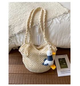 Detailed close-up of cream woven cotton bag with textured ring handle and plush duck charm