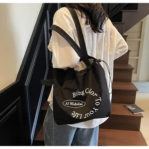 Detail of black drawstring canvas tote with white Bring Color To Your Life slogan