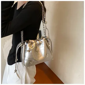 Détail du sac bandoulière argenté avec papillons métalliques 3D et texture matelassée