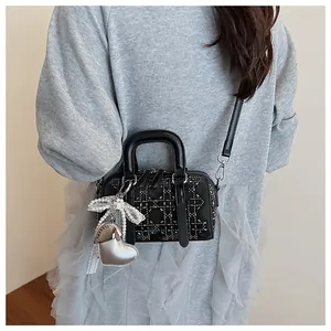 Close-up of quilted mini bag with silver studs, heart pendant and pearl bow detail