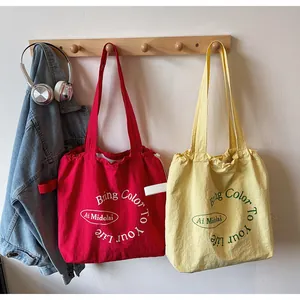 Detail of red and yellow canvas tote bags with drawstring design and printed typography