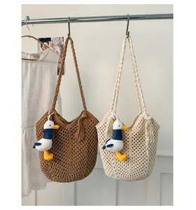 Detail of woven beach bags with hollow crochet patterns, tassels and a cute seagull charm
