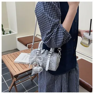 Detail of silver barrel bag featuring rhinestone grid, pearl bow, and heart charm