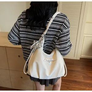Detail of beige hobo bag showing bow, heart pendant and silver star charm accents