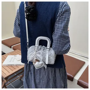 Detail of silver denim Boston bag featuring rhinestone studs and heart charm with bow