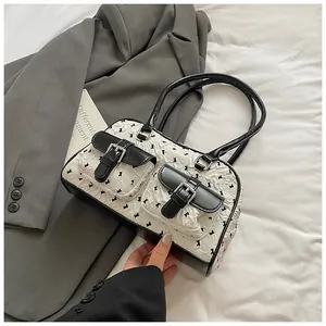Detail shot of the lace bow patterns and black leather pockets on white pleated bag
