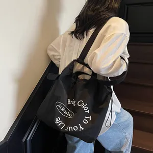Black canvas tote bag with contrast lettering and drawstring closure for daily casual wear