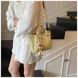 Detalle del bolso crema con textura de lichi y asa trenzada mostrado en escaleras