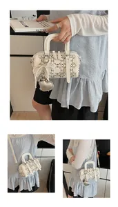 Detail of cream denim Boston bag with pearl bow and diamond heart pendant charm