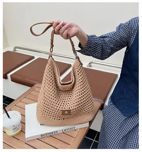Detail of hollow knit shoulder bag with brown leather strap and metallic buckle