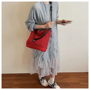 Detailed view of red hollow knit shoulder bag with leather strap on a model