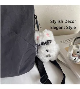 Dettaglio ciondolo cane di peluche bianco con collare su borsa in nylon nero