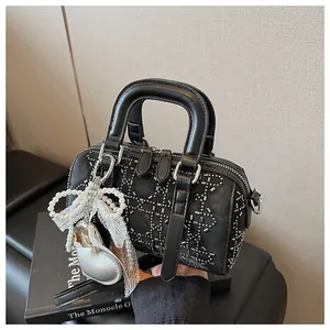 Detail of denim Boston bag with silver studs, lace bow, and pearl charm pendants
