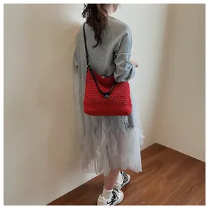 Detail view of red hollow knit shoulder bag with black leather strap and limitless label