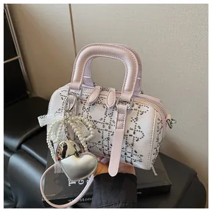 Detail of pink and white denim Boston bag with silver studs and heart pearl charm
