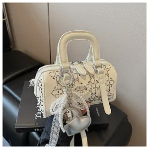 Detail of white cylinder Boston bag with silver rivets and heart pearl charm