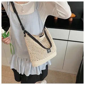 Detail of beige crochet hobo bag with adjustable black strap and woven mesh texture