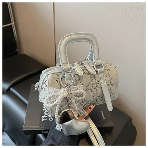 Detailed close-up of a silver denim Boston bag with rhinestones and pearl bow charms