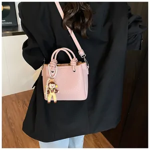 Detalle del bolso saco de cuero rosa con asa anudada y colgante de muñeca infantil