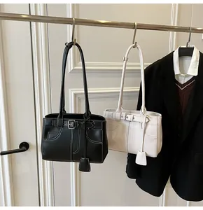 Dettaglio di borse tote in pelle nera e beige con cuciture a contrasto e fibbie in metallo