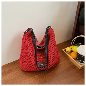 Detail of red crochet knit tote bag featuring black straps and a minimalist logo patch